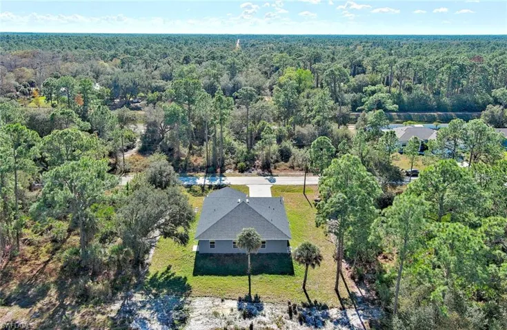 Aerial view of property and surrounding area featuring a forest