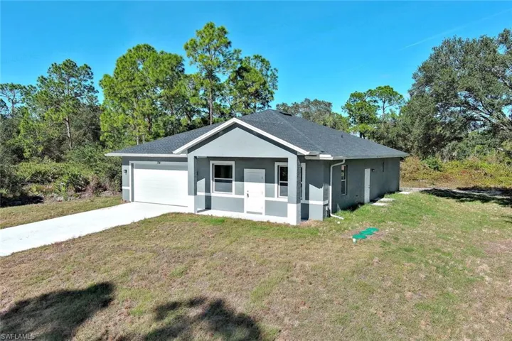 Single story home with a front yard, stucco siding, driveway, and a garage
