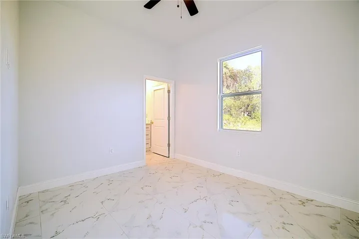 Empty room featuring marble finish flooring and a ceiling fan