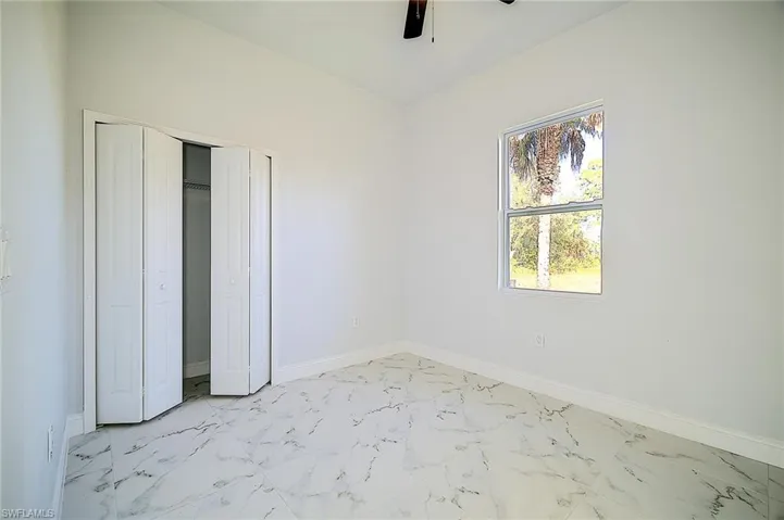 Unfurnished bedroom featuring light marble finish floors, a closet, and a ceiling fan