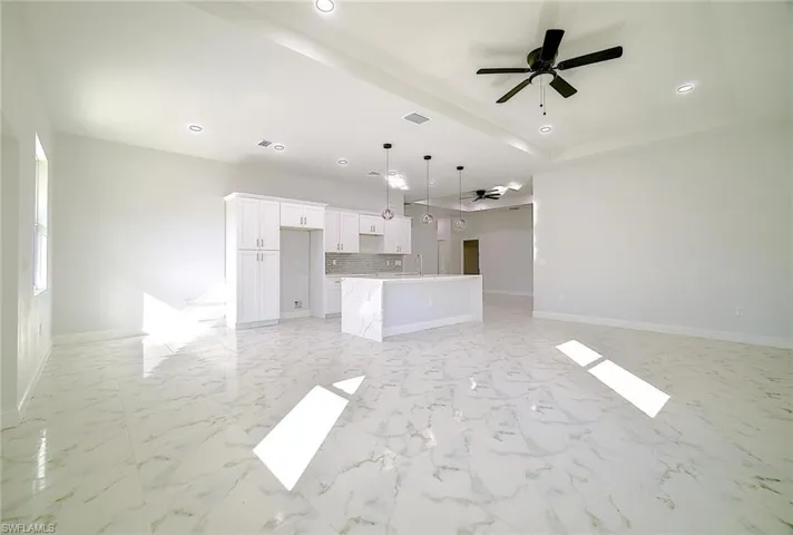 Unfurnished living room with a ceiling fan, light marble finish flooring, and recessed lighting