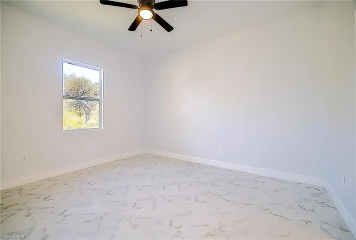 Unfurnished room with light marble finish flooring and ceiling fan
