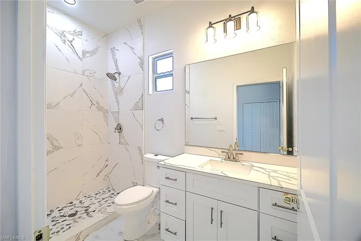 Full bathroom featuring a shower stall, vanity, and light marble finish flooring