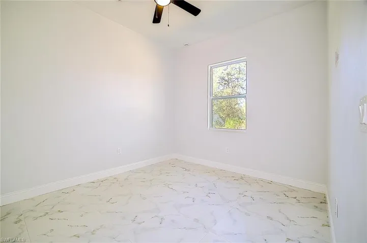 Unfurnished room with marble finish flooring and a ceiling fan