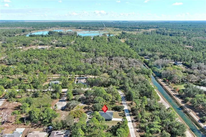 Aerial view of property's location featuring a large body of water and a heavily wooded area