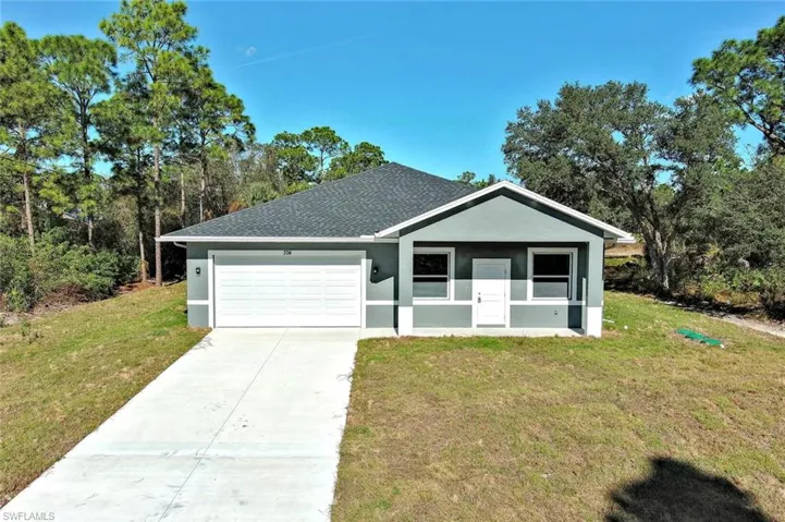 View of front of home with stucco siding, roof with shingles, and a front yard