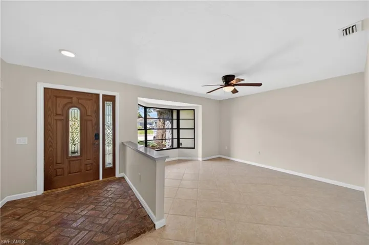 Entry foyer with brick-patterned flooring and decorative glass front door