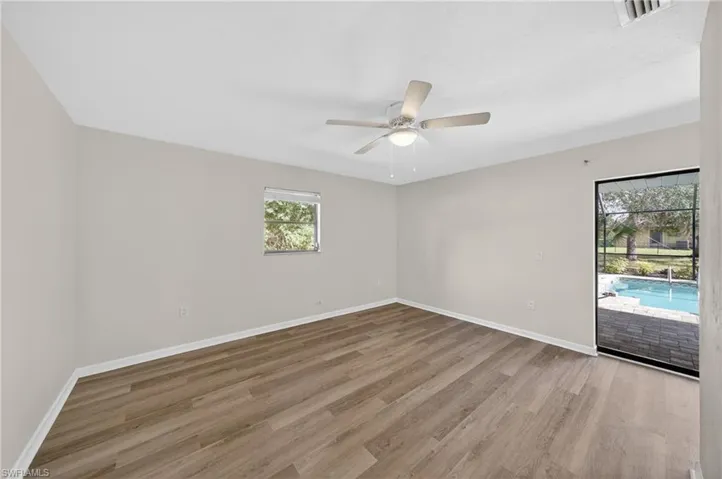 Spacious room featuring wood-finish flooring, a contemporary ceiling fan with integrated lighting, and a window for natural illumination