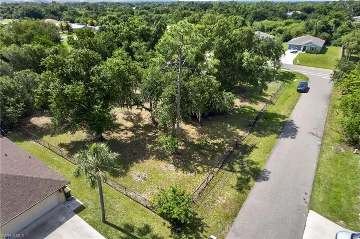 Substantial lot featuring mature trees, partial fencing, and direct paved road frontage