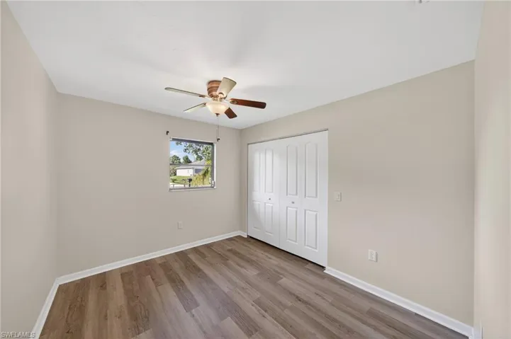 Room featuring wood-finish flooring, neutral wall tones, a ceiling fan with integrated lighting, and a double bi-fold closet