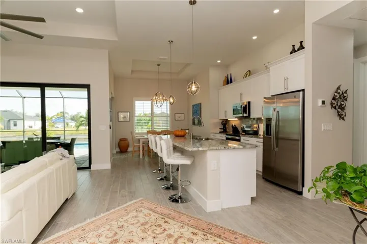 Kitchen with pendant lighting, light wood-type flooring, an island with sink, white cabinetry, and stainless steel appliances