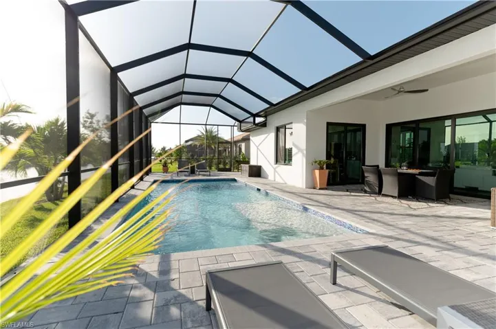 View of swimming pool featuring glass enclosure, ceiling fan, and a patio area