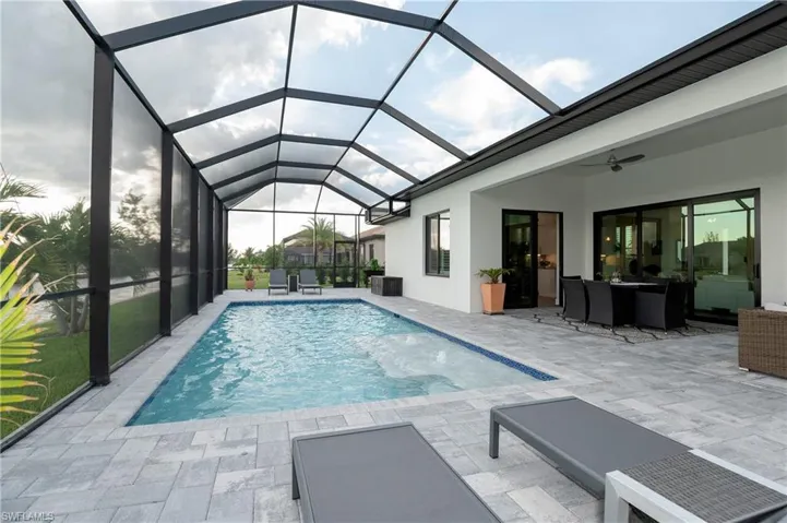 View of swimming pool featuring glass enclosure, ceiling fan, and a patio area