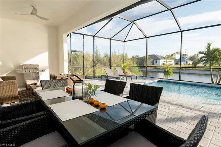 View of patio / terrace with grilling area, a water view, ceiling fan, and a lanai