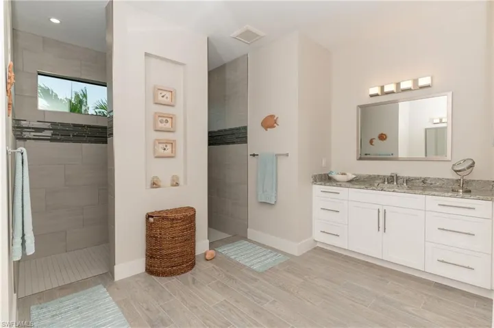 Bathroom featuring tiled shower and vanity