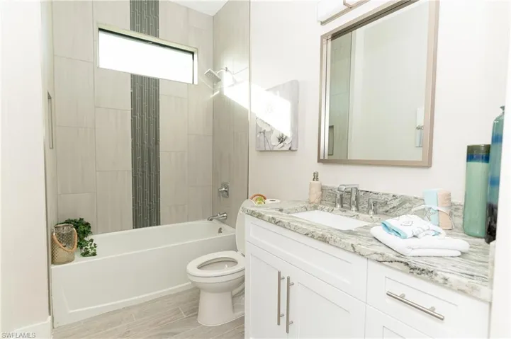 Full bathroom featuring hardwood / wood-style floors, vanity, toilet, and tiled shower / bath