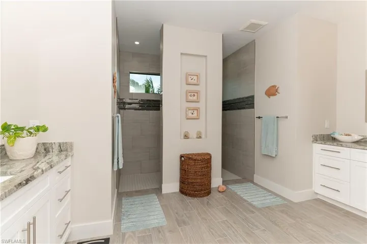 Bathroom featuring tiled shower and vanity
