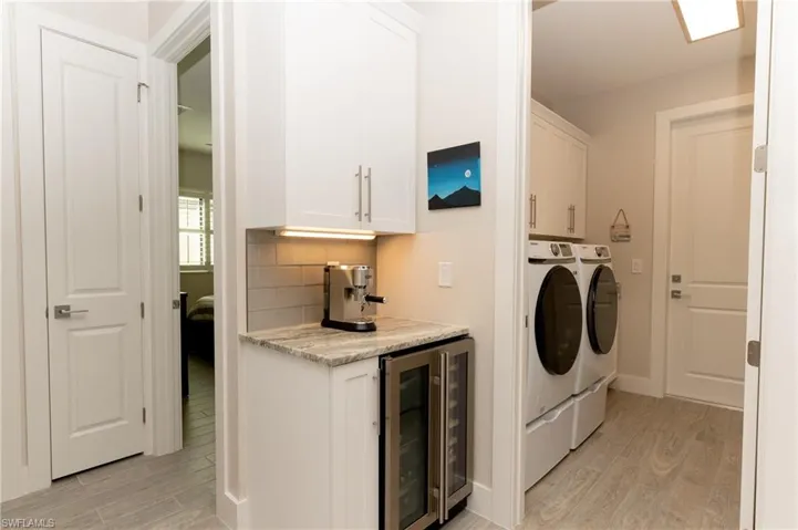Laundry room featuring light hardwood / wood-style floors, cabinets, independent washer and dryer, and beverage cooler