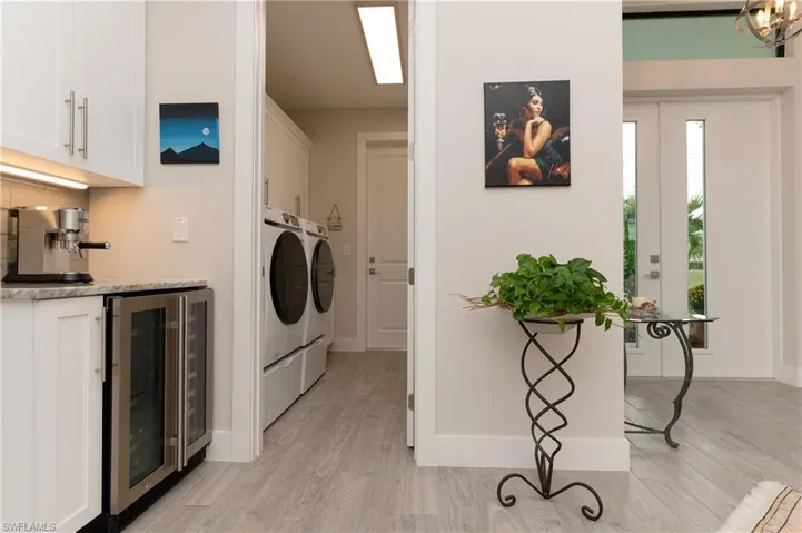 Laundry area featuring separate washer and dryer, cabinets, beverage cooler, and light wood-type flooring