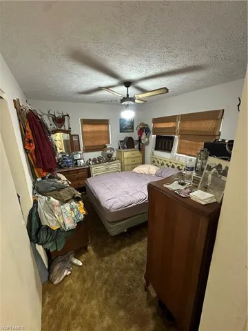 Bedroom featuring dark colored carpet, a textured ceiling, and ceiling fan