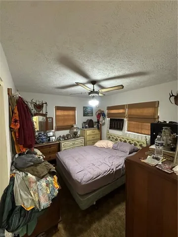 Carpeted bedroom featuring a textured ceiling and a ceiling fan