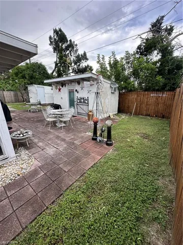 Fenced backyard featuring a patio area and an outbuilding