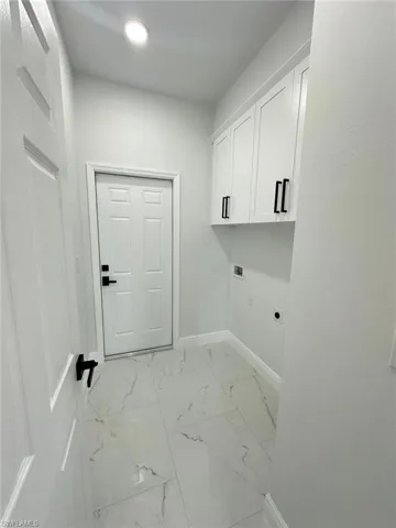 Laundry room featuring marble finish floor, baseboards, hookup for a washing machine, cabinet space, and hookup for an electric dryer