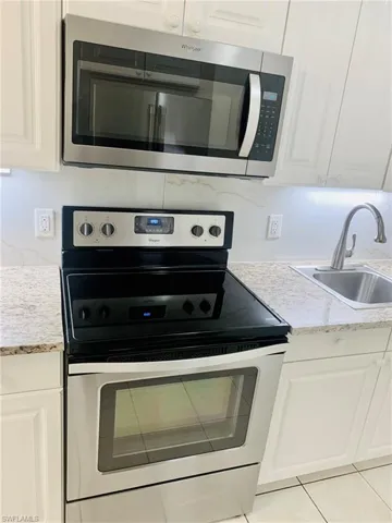 Kitchen featuring appliances with stainless steel finishes, white cabinetry, and decorative backsplash
