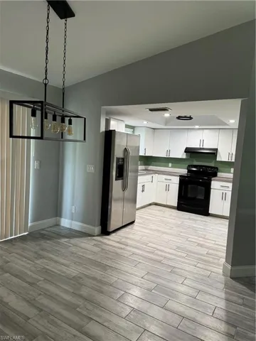 Kitchen featuring white cabinetry, light hardwood / wood-style flooring, and stove
