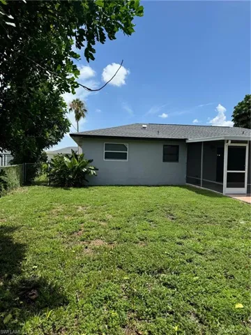 Rear view of property featuring a fire pit, a sunroom, and a lawn