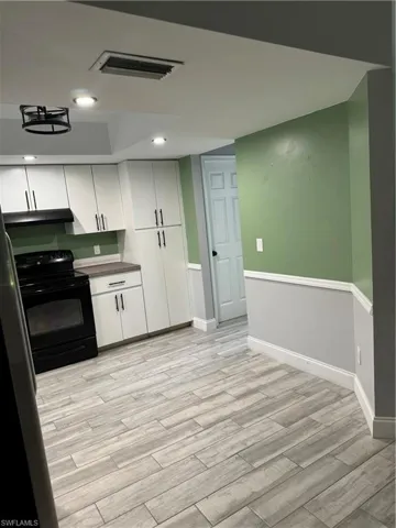 Kitchen with range, dishwashing machine, refrigerator, white cabinets, and sink
