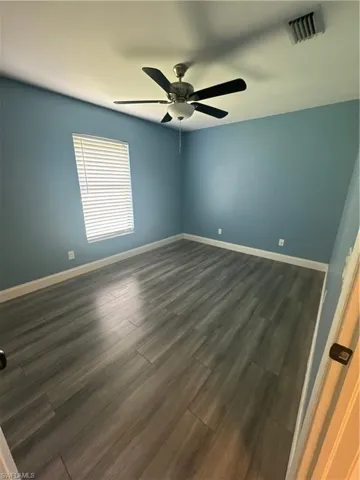 Unfurnished bedroom featuring dark hardwood / wood-style floors, a closet, and ceiling fan
