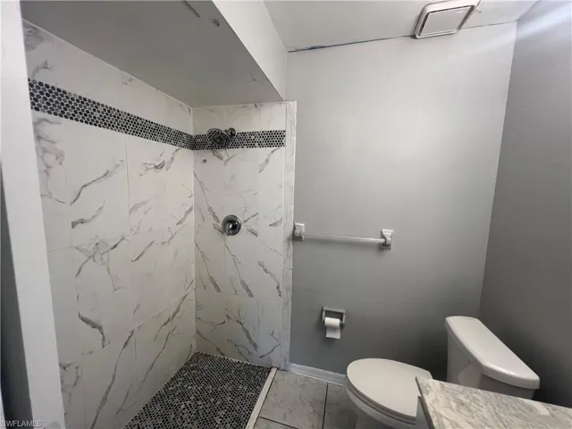 Bathroom with tile patterned floors and a tile shower