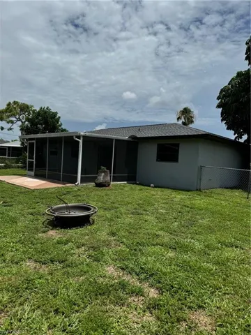 Rear view of house featuring a sunroom and a lawn