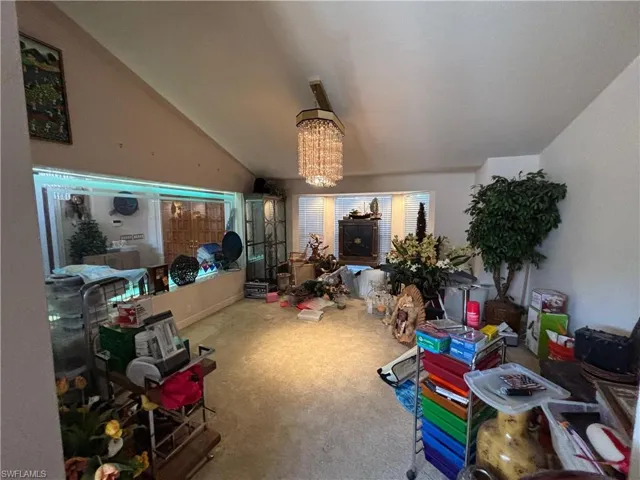Carpeted living area with suspended lighting and vaulted ceiling