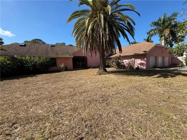 Rear view of property with a garage, a lawn, and stucco siding