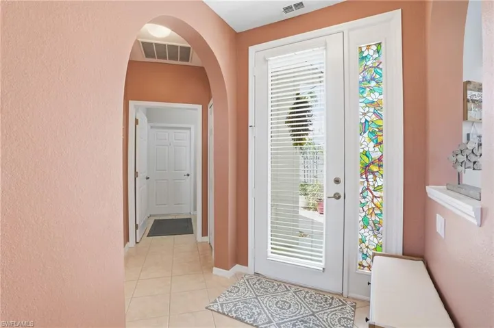 Entrance foyer with a textured wall, arched walkways, and light tile patterned floors