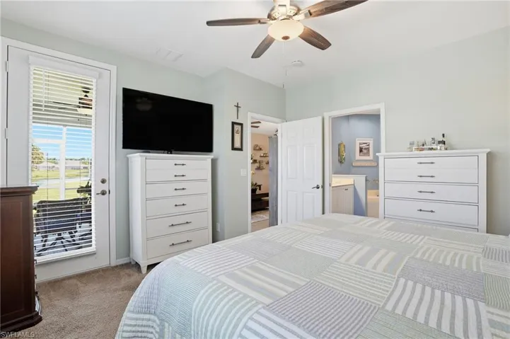 Bedroom featuring access to exterior, light colored carpet, a ceiling fan, and ensuite bath