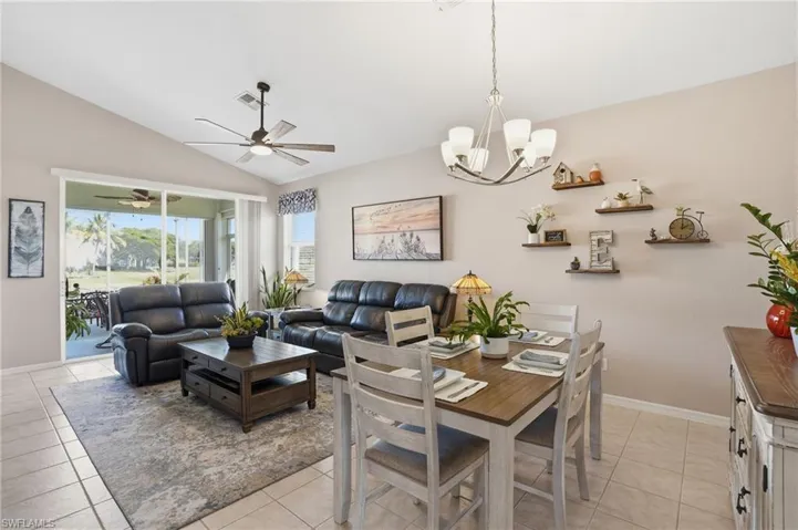 Dining room featuring lofted ceiling, a chandelier, light tile patterned floors, and ceiling fan
