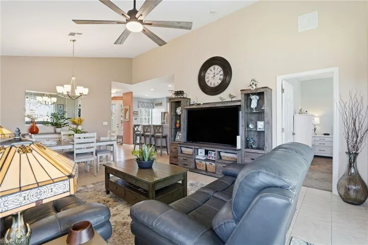 Living room with high vaulted ceiling, light tile patterned flooring, ceiling fan, and a chandelier