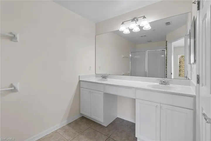 Dual vanity with integrated sinks, white cabinetry, and a full-width mirror with overhead lighting