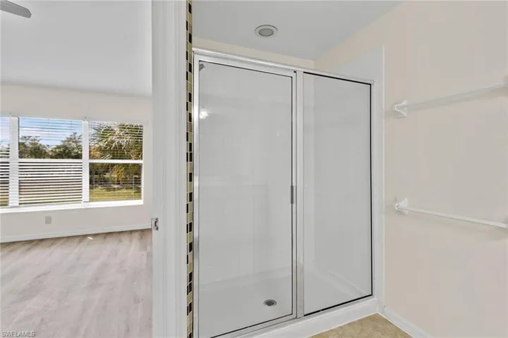 Glass-enclosed shower with tile surround, recessed lighting, and adjacent closet shelving