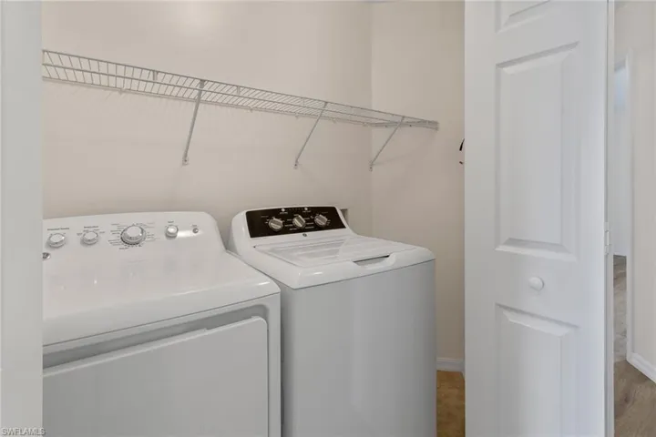 Dedicated laundry area featuring a wire shelving unit, a white paneled door, and neutral wall paint