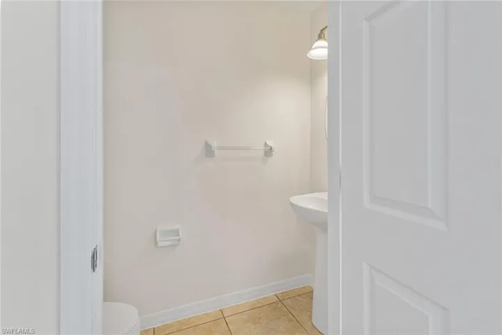 Pedestal sink, ceramic tile flooring, and wall-mounted light fixture