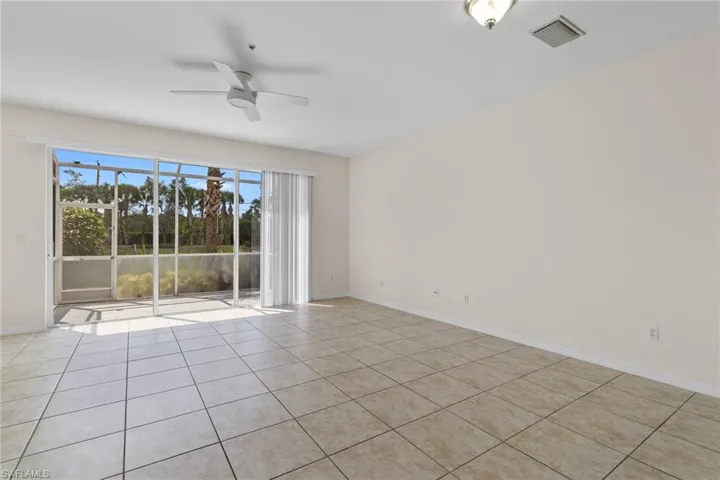 Spacious room featuring tile flooring, a ceiling fan, and a light fixture, with a full-wall glass slider opening to a screened-in patio