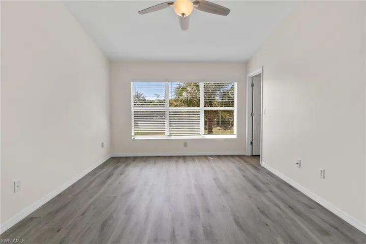 Neutral wall tones, wood-finish flooring, and a ceiling fan with integrated lighting