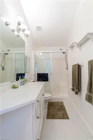 Bathroom with toilet, vanity, tile patterned floors, and a shower with shower door