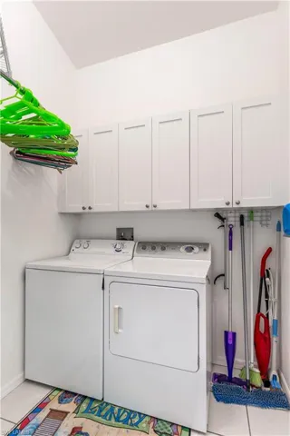 Laundry room with cabinets, washer and dryer, and light tile patterned floors