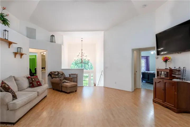 Living room featuring high vaulted ceiling, light hardwood / wood-style floors, and a chandelier