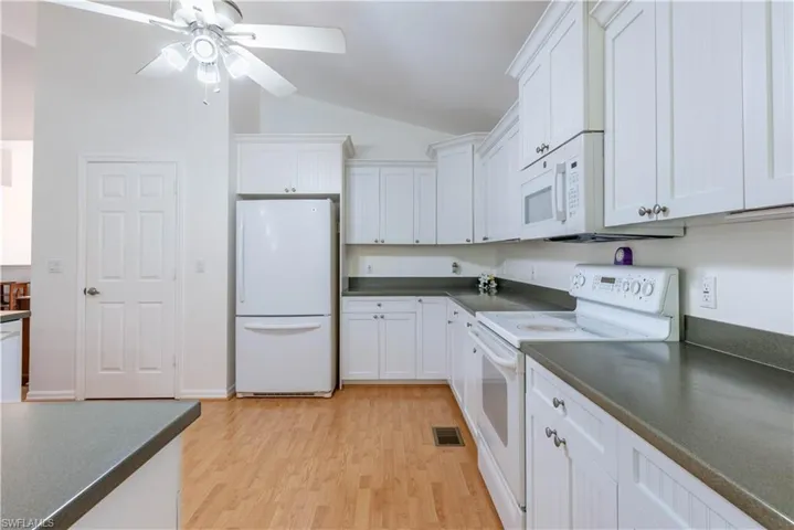Kitchen with white cabinetry, light hardwood / wood-style floors, white appliances, lofted ceiling, and ceiling fan